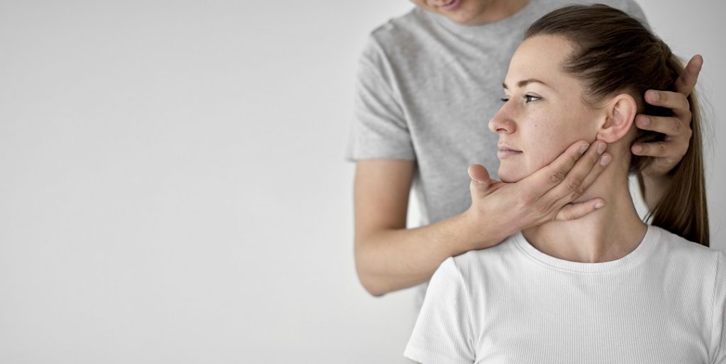 fisioterapeuta masculino realizando terapia física con paciente femenina con artrosis de mandícula.