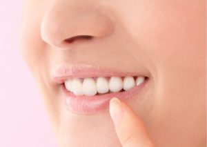 mujer se toca un diente para detectar si existe movilidad dental.