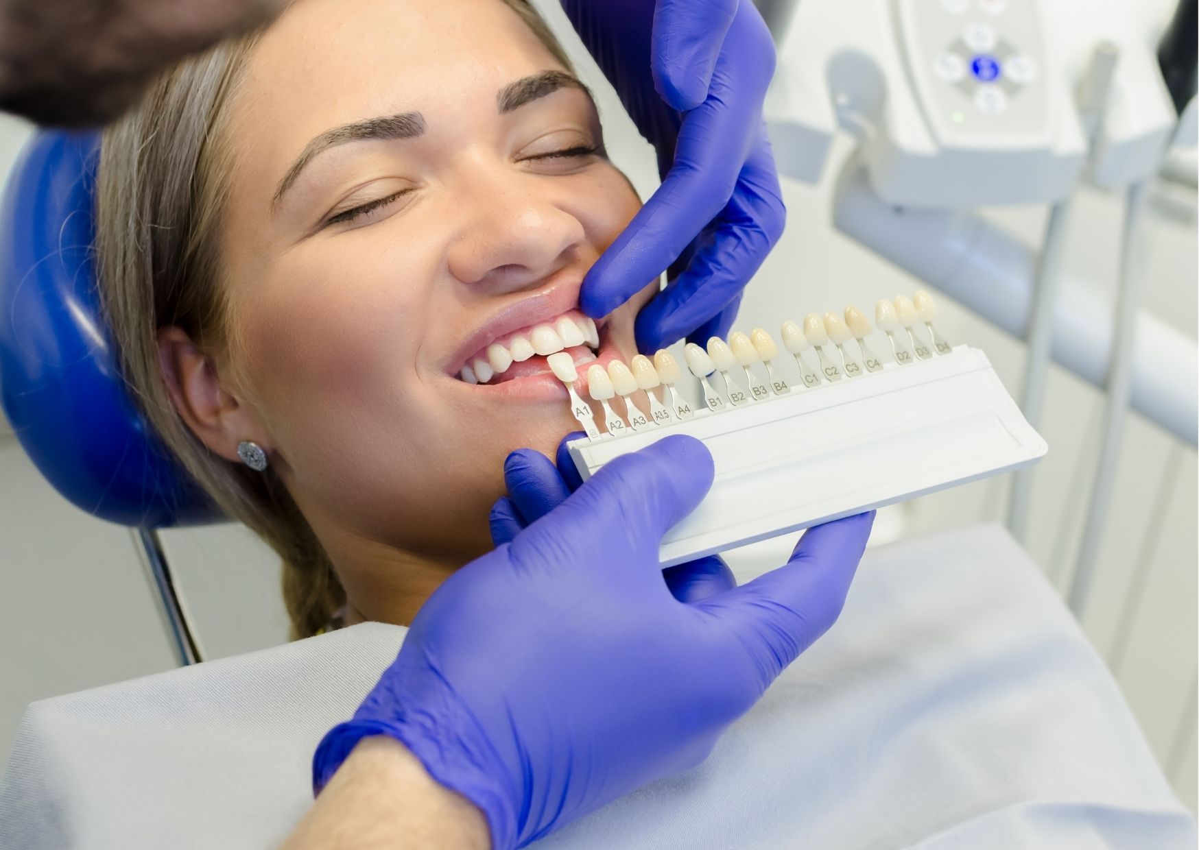Dentista prueba distintos tonos de color para diente de paciente recostada en silla dental. tema: blanqueamiento dental para pacientes con endodoncia