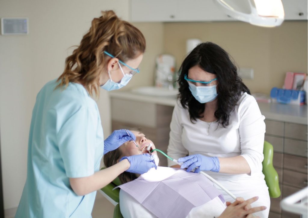 Dentista y asistente dental atendiendo a una paciente recostada en el sillón. Tema: cuánto tarda una caries en destruir un diente.