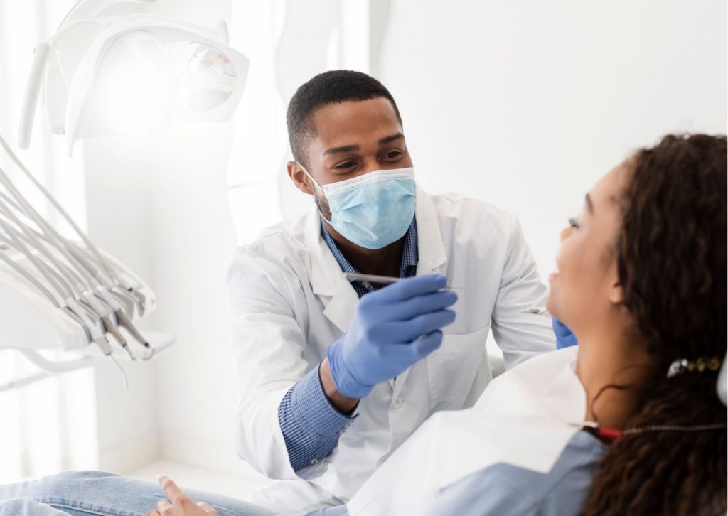 Dentista atendiendo a una paciente recostada en el sillón dental que tienen alveolitis.