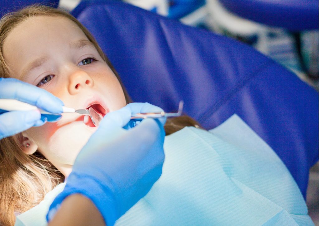 Niña rubia recostada en el sillón dental es examinada por el dentista. tema: caries profundas en niños