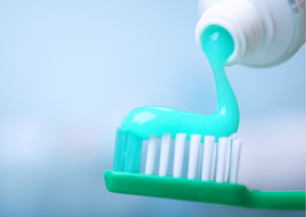Plano cerrado de pasta dental calipso siendo vertida en un cepillo de dientes color verde. tema: para qué sirve el flúor en los dientes, nota Everest Life 
