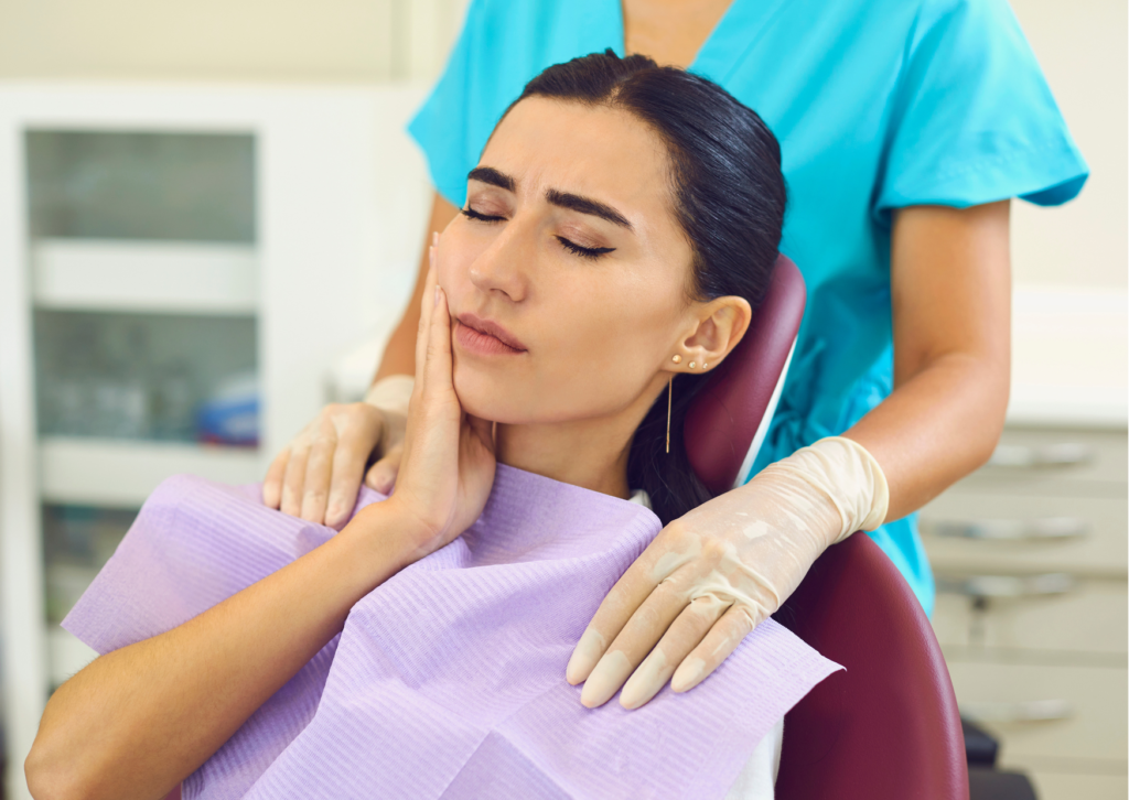 
Mujer morena sentada en la silla del dentista toca con su mano el costado derecho de la cara , insinuando dolor severo en esa zona. Tema Dolor orofacial para Blog Everest Life.
