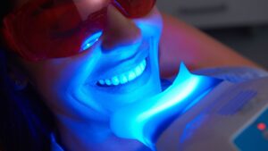 Mujer feliz sometiéndose a un tratamiento de blanqueamiento dental en una clínica