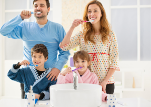Familia feliz cepilla sus dientes juntos frente al espejo. tema: cuida la salud dental de tus hijos para Everest Life