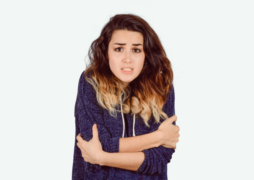 Retrato de una joven mujer que se abraza a sí misma por el frío. Tema: castañear los dientes por el frío para el blog dental de Clínica Everest.